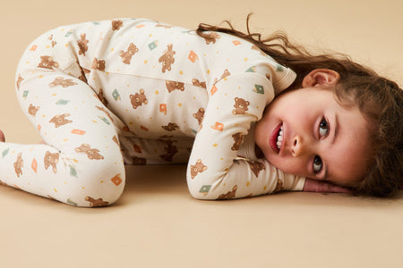 Toddler in a cozy, bear-themed winter jacket and trousers, holding a teddy bear, perfect for chilly days.
